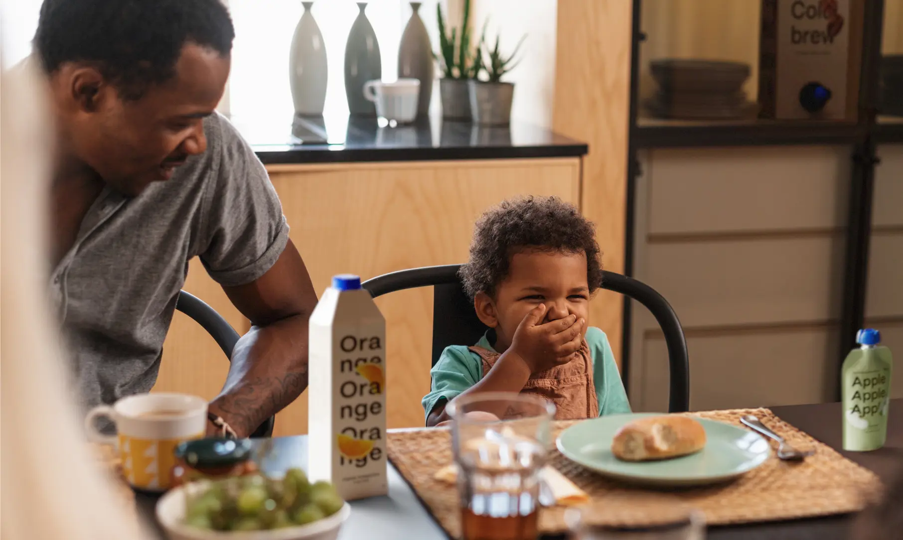 bambino che fa colazione con succo di arancia e pane